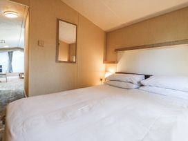 A bedroom with a bed and mirror at White Hart Caravan in Battle