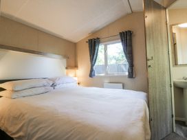 A bedroom with a double bed and window at White Hart Caravan in Battle