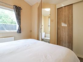 A bedroom with a bed and a view of a toilet at White Hart Caravan in Battle