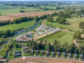 An aerial view of a holiday park with caravans and cabins near a river and fields at Nature's Nook - Billing Aquadrome in Billing Aquadrome Holiday Park
