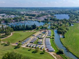 An aerial view of a holiday park with rows of caravans near a river and a lake at Nature's Nook - Billing Aquadrome in Billing Aquadrome Holiday Park