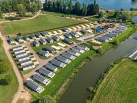 An aerial view of a holiday park with rows of static caravans near a river at Nature's Nook - Billing Aquadrome in Billing Aquadrome Holiday Park