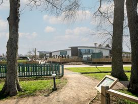 A park area with trees and a green fence facing a modern building labeled The Venue at Billing Aquadrome Holiday Park