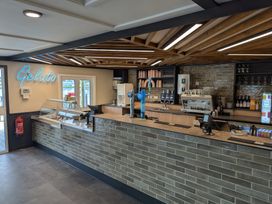 An ice cream and coffee counter with gelato sign glasses cups and coffee machine at a cafe
