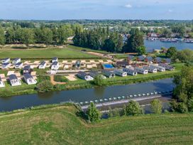 A river with a weir and rows of mobile homes beside a grassy area at Meadowview - Billing Aquadrome in Billing Aquadrome Holiday Park