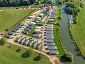 An aerial view of a caravan park with rows of caravans next to a river at Meadowview - Billing Aquadrome in Billing Aquadrome Holiday Park