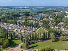 An aerial view of a holiday park with numerous caravans surrounded by trees and small bodies of water at Meadowview Billing Aquadrome in Billing Aquadrome Holiday Park