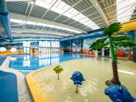 An indoor swimming pool area with a shallow paddling pool featuring blue and yellow animal shaped decorations and a palm tree at Meadowview - Billing Aquadrome in Billing Aquadrome Holiday Park