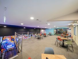 An indoor seating area with tables and chairs next to a glass railing overlooking a lower floor arcade at Meadowview - Billing Aquadrome in Billing Aquadrome Holiday Park