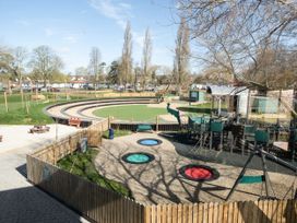 An outdoor playground with trampolines slide climbing structures and a circular seating area at Meadowview - Billing Aquadrome in Billing Aquadrome Holiday Park