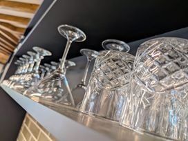 A row of upside down wine glasses and etched drinking glasses on a shelf