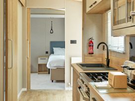 A kitchen with a stove and sink leading to a bedroom at Meadowview - Billing Aquadrome