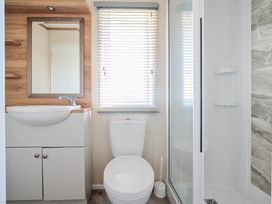 A bathroom with a toilet sink cabinet mirror window with blinds and shower at Serenity Shores - Billing Aquadrome in Billing Aquadrome Holiday Park