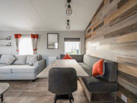 A living room with a sofa a dining table chairs and cushions at Billing Bliss - Billing Aquadrome in Billing Aquadrome Holiday Park