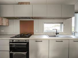 A kitchen with a stove, oven, sink, cabinets, and a window at Billing Bliss - Billing Aquadrome in Billing Aquadrome Holiday Park