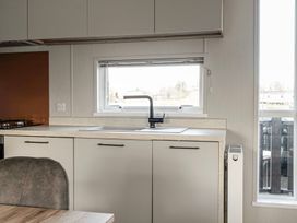 A kitchen area with a sink under a window a countertop cabinets and a radiator at Billing Bliss - Billing Aquadrome in Billing Aquadrome Holiday Park