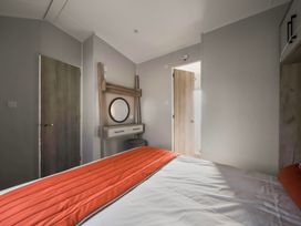 A bedroom with a bed with an orange bedspread a vanity with a round mirror and two doors at Billing Bliss - Billing Aquadrome Holiday Park