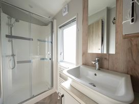 A bathroom with a shower enclosure and a sink with a mirror at Billing Bliss Billing Aquadrome Holiday Park