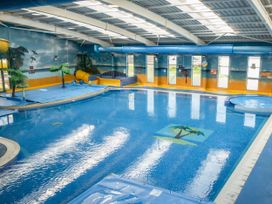 An indoor swimming pool with slides and palm tree decorations at Tranquil Waters - Billing Aquadrome