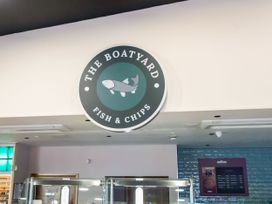 A fish and chips restaurant sign on a wall above glass display counters at The Boatyard
