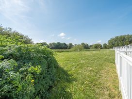A grassy field with bushes on the left and a row of white fences on the right at Tranquil Waters - Billing Aquadrome Billing Aquadrome Holiday Park