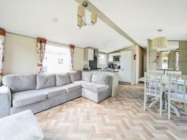 An open plan living room kitchen and dining area with a grey corner sofa wooden floor and dining table with chairs at Tranquil Waters - Billing Aquadrome in Billing Aquadrome Holiday Park