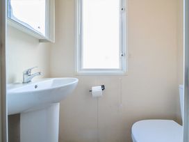 A bathroom with a sink toilet paper holder and toilet at Tranquil Waters - Billing Aquadrome in Billing Aquadrome Holiday Park