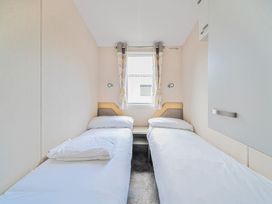 A bedroom with two single beds separated by a small bedside table and a window at Tranquil Waters - Billing Aquadrome in Billing Aquadrome Holiday Park
