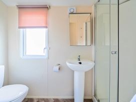 A bathroom with a toilet sink shower and a window with a pink blind at Tranquil Waters - Billing Aquadrome in Billing Aquadrome Holiday Park