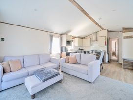 A living room with two sofas a small table and kitchen dining area at Aquadrome Abode - Billing Aquadrome Holiday Park