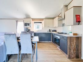 A kitchen with dining table and chairs beside a window and cabinets at Aquadrome Abode - Billing Aquadrome Holiday Park