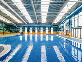 An indoor swimming pool with a water slide and large windows at Lakeside Lullaby  Billing Aquadrome Holiday Park