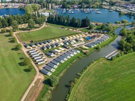 An aerial view of a holiday park with rows of caravans by a river and a marina with boats at Moonlit Skylight - Billing Aquadrome in Billing Aquadrome Holiday Park