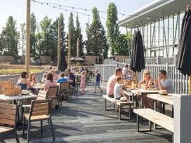 An outdoor dining area with people at tables and umbrellas at Brookside Bliss - Billing Aquadrome