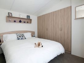 A bedroom with a bed and wardrobe at Mariner's Meadow - Hayling Island