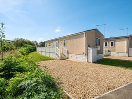 A mobile home with a gravel driveway and surrounding greenery at Island Breeze - Hayling Island in Hayling Island Holiday Park