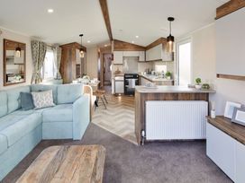 A living room with a sofa and kitchen area at Island Breeze - Hayling Island