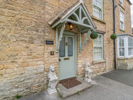 An entrance with a green door and lion statues at The Cottage in Stow-On-The-Wold