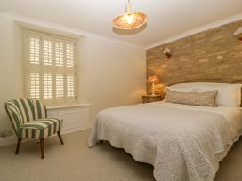 A bedroom with a bed, side table, and chair at The Cottage in Stow-On-The-Wold