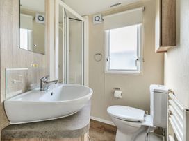 A bathroom with a sink counter mirror shower toilet window and wall cabinet at Golden Dune - Hayling Island Hayling Island Holiday Park