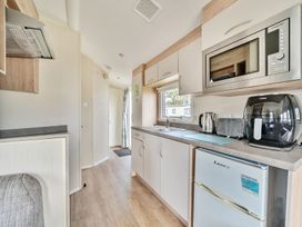 A kitchen area with microwave kettle toaster air fryer and fridge at Golden Dune - Hayling Island in Hayling Island Holiday Park