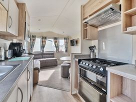 A kitchen and living area with cabinets stove microwave sofa and dining table at Golden Dune - Hayling Island in Hayling Island Holiday Park