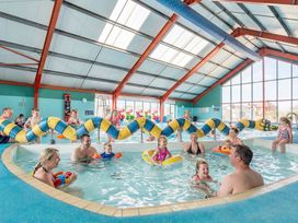 An indoor pool with children and adults playing with water toys at The Lookout - Hayling Island Holiday Park