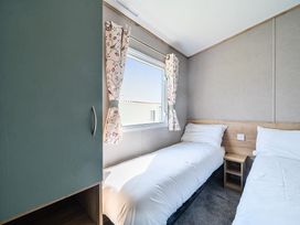 A bedroom with two single beds a window and a wardrobe at Dune Delight - Hayling Island Holiday Park