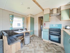 A kitchen and dining area with green cabinets and a corner bench seat at Dune Delight - Hayling Island in Hayling Island Holiday Park