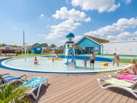 An outdoor pool area with a play structure at Dune Delight - Hayling Island