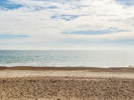 A pebble beach with the ocean and a partly cloudy sky at Coastal Comfort - Hayling Island in Hayling Island Holiday Park