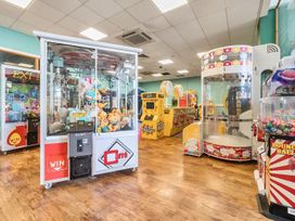 An arcade room with claw machines and game machines on a wooden floor at Beachcomber's Base - Hayling Island Holiday Park
