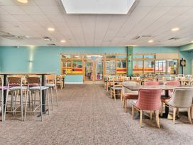 A large dining area with multiple tables and chairs and a dartboard on the wall at Beachcomber's Base - Hayling Island in Hayling Island Holiday Park