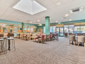 A dining area with multiple tables and chairs and large windows at Beachcomber's Base - Hayling Island Holiday Park